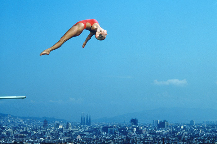 Tracey Miles, saltadora de la Gran Bretanya, és fotografiada mentre salta a la Piscina Municipal de Montjuïc, amb la Sagrada Família al fons.