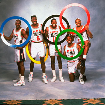 L’equip de bàsquet dels Estats Units subjectant les anelles olímpiques: Michael Jordan (9), Patrick Ewing (6), Magic Johnson (10), Karl Malone (7) i Charles Barkley (12).