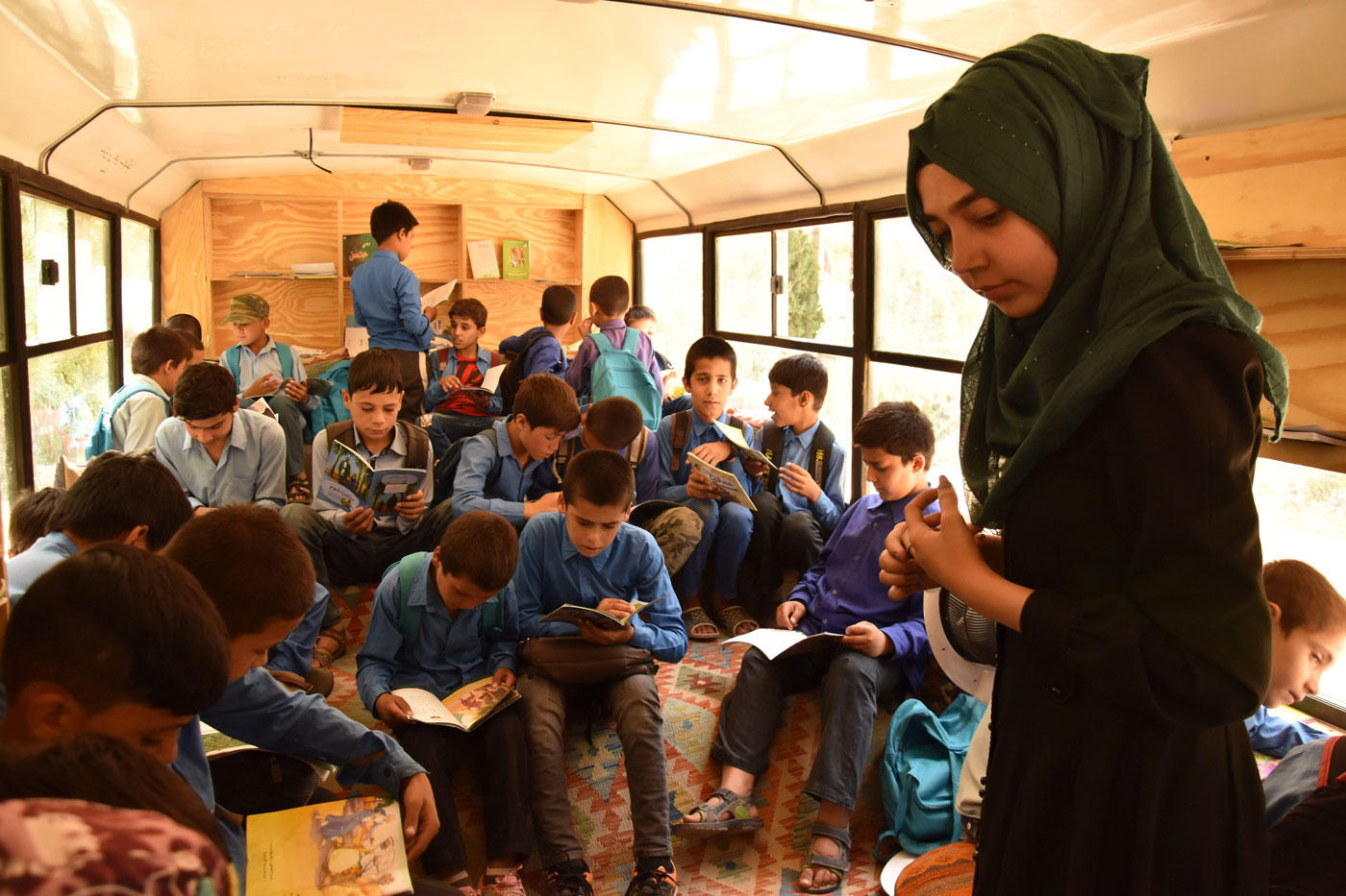 Una educadora comprueba qué libros están leyendo los niños en uno de los autobuses de la asociación Charmaghz, este domingo en Kabul.