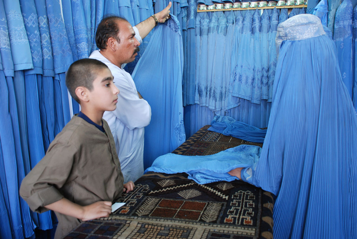 Un hombre muestra un burka a una clienta. Muchas mujeres utilizan esta prenda de vestir en Afganistán.