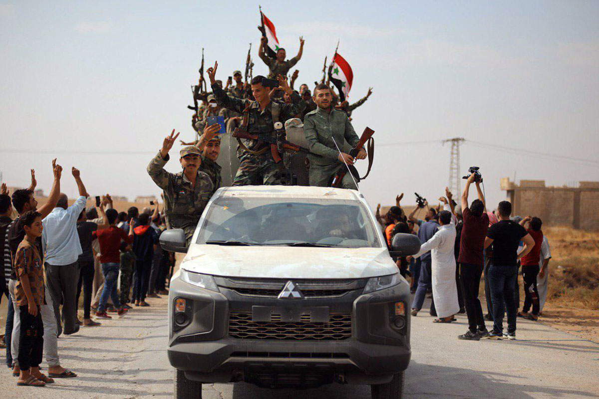 Un camión con soldados del régimen de Asad son recibidos por parte de la población del Kurdistán sirio en la localidad de Ain Issa.
