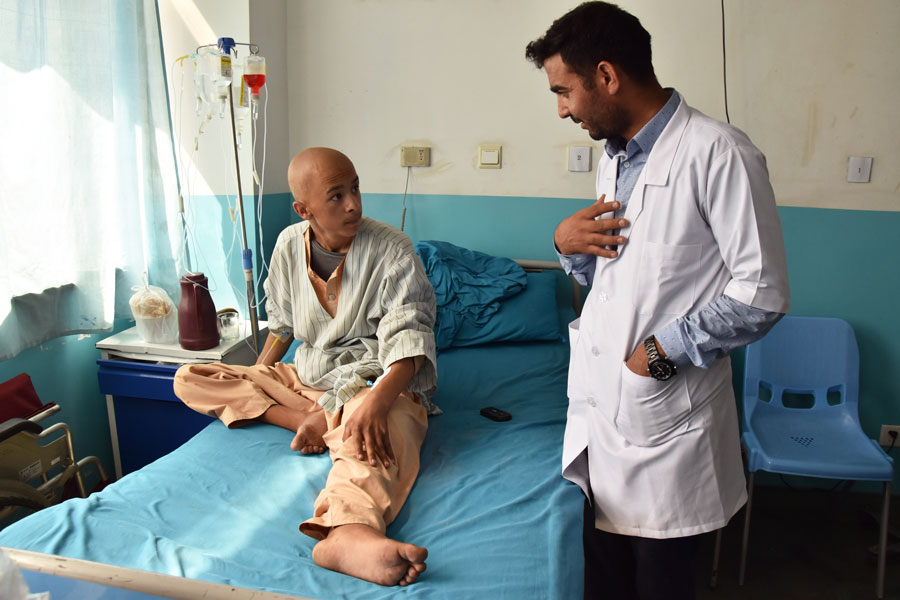 El doctor Kifayatullah Safi habla con un paciente en la unidad oncológica del hospital Jamhuriat, de Kabul.